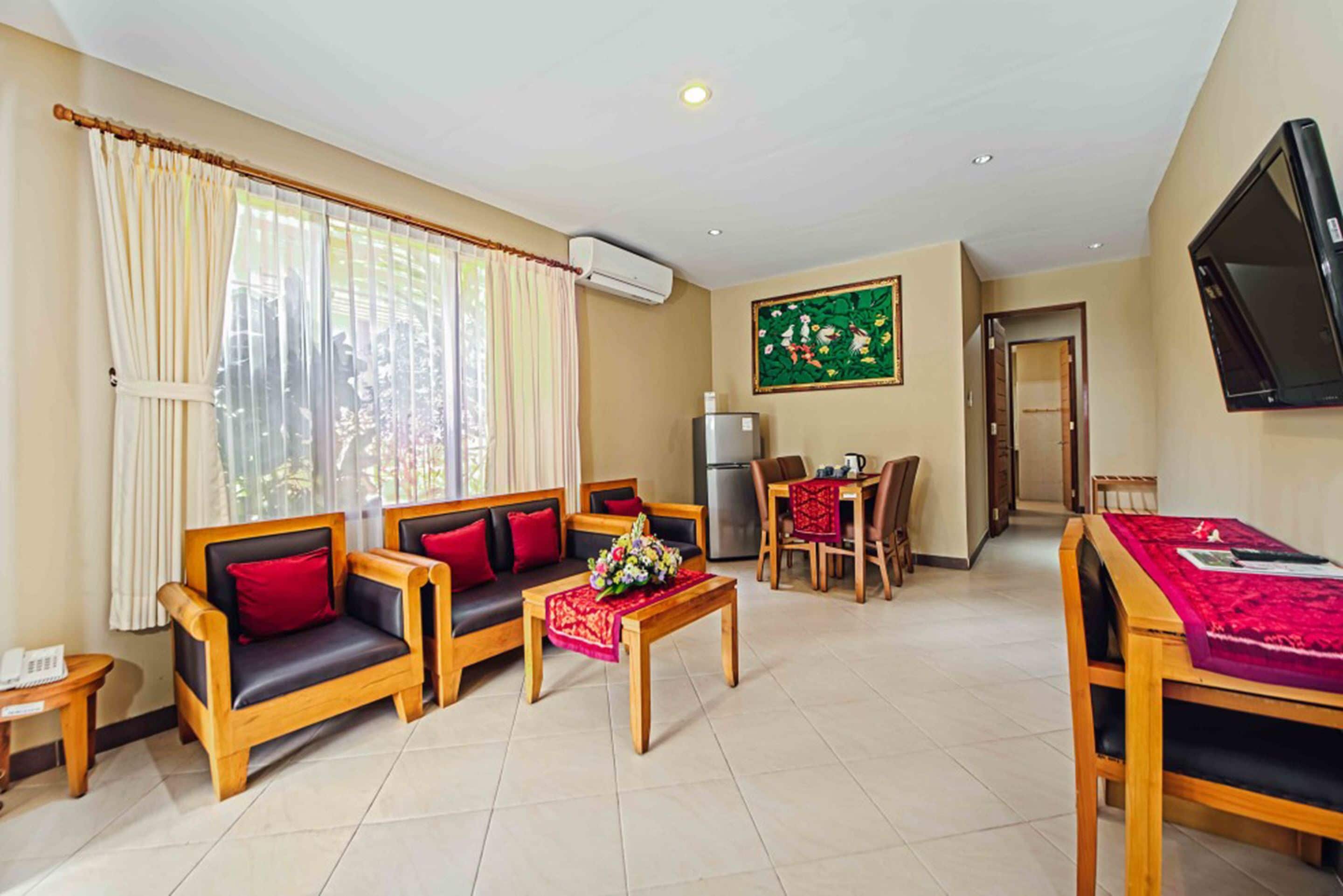 A living room with a sofa set, a coffee table, a dining table with chairs, and a TV mounted on the wall.