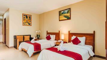 A hotel room with two beds, each with white linens and red accents, a wooden headboard, and a painting on the wall.