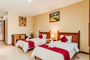 Habitación de hotel con dos camas, cada una con ropa blanca y detalles rojos, cabeceros de madera y un cuadro en la pared.