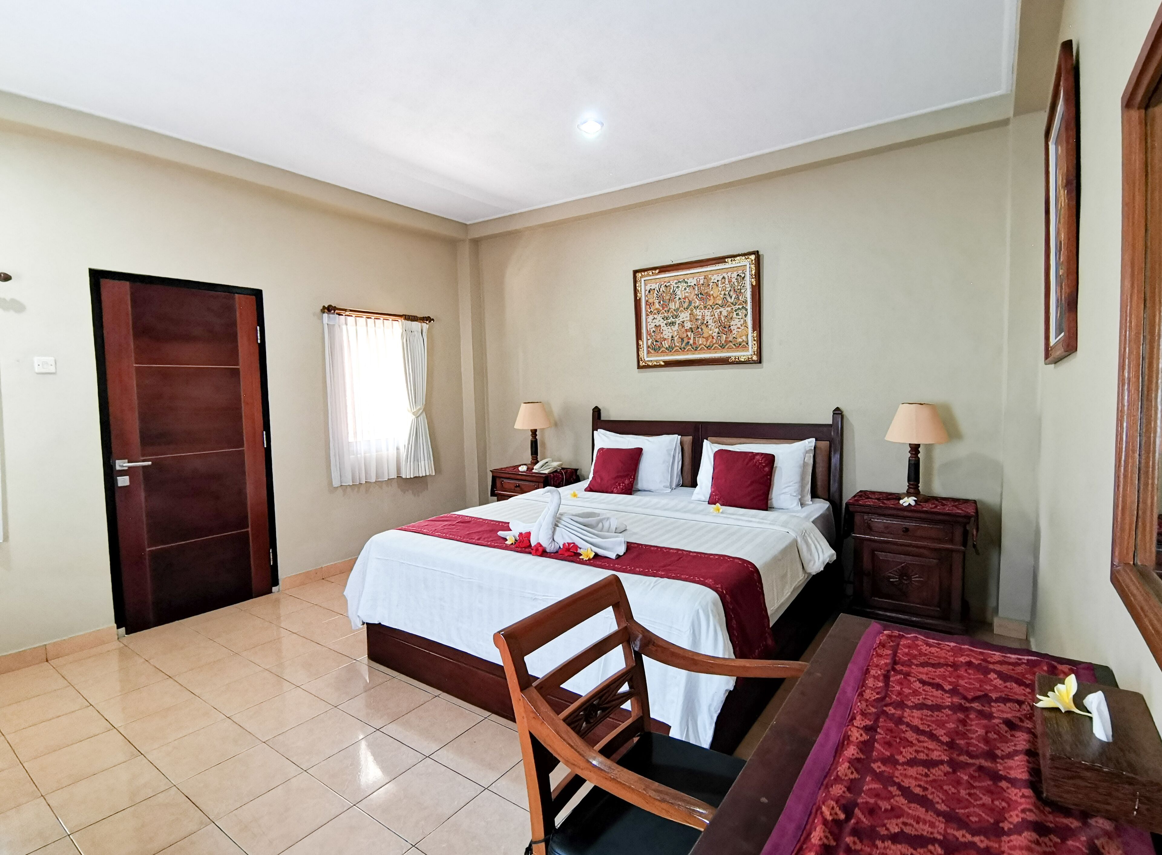 A neatly arranged hotel room with a large bed, two bedside tables, a wooden chair, a desk, and a large mirror.