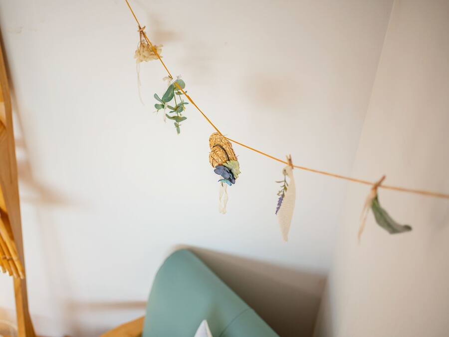 A string of dried flowers and leaves hanging on a wall.