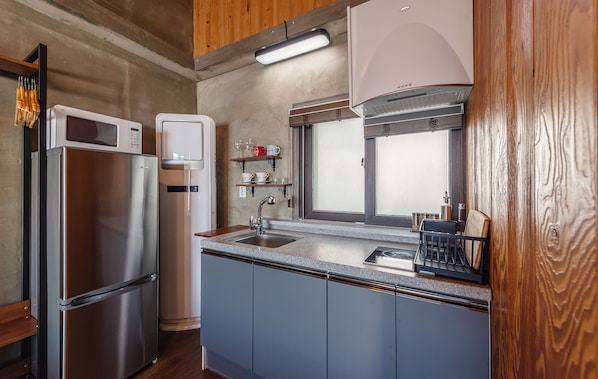 Una cocina compacta con un refrigerador de acero inoxidable, un microondas y un lavamanos.