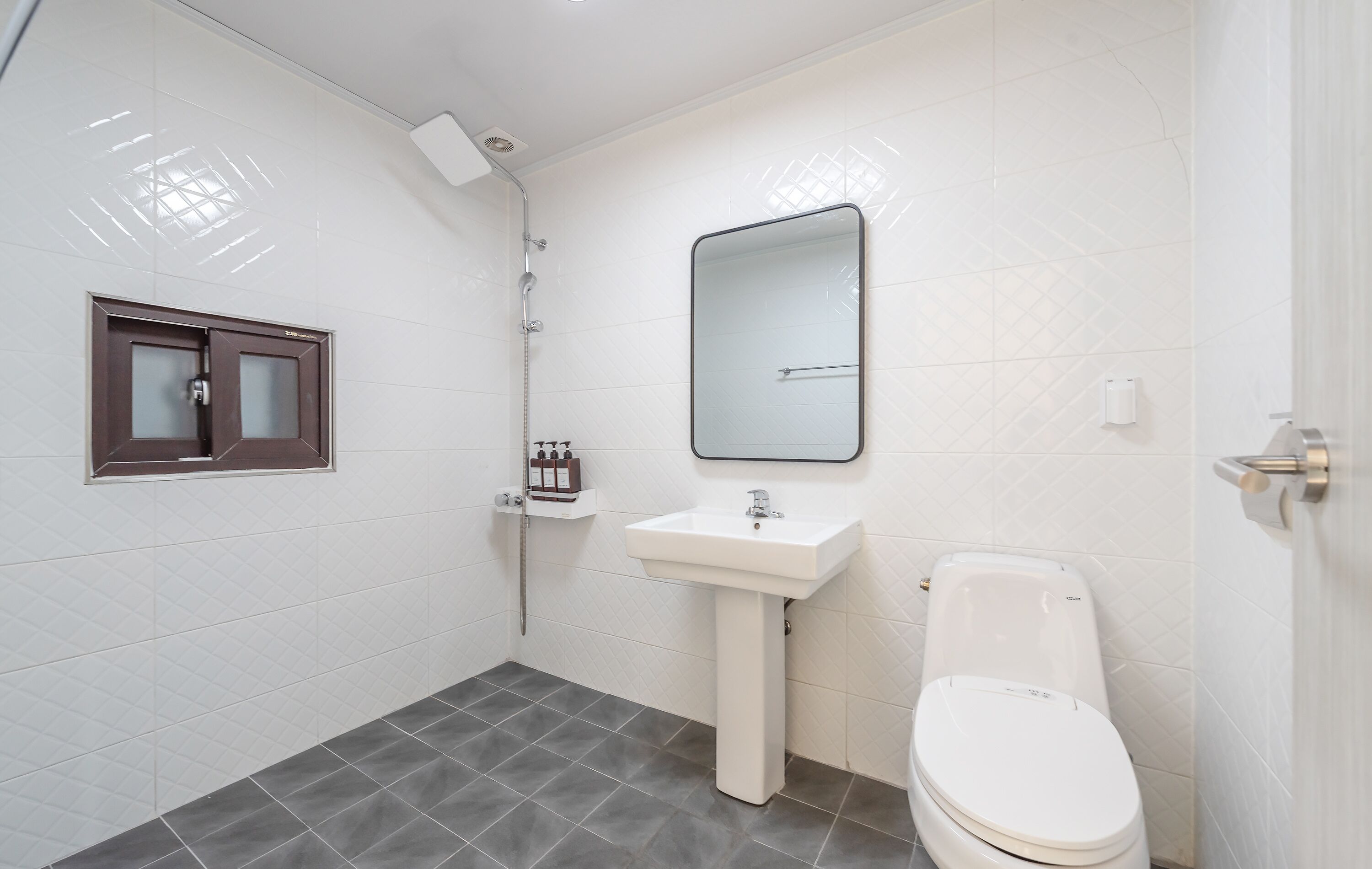 A bathroom with a shower, sink, and toilet.