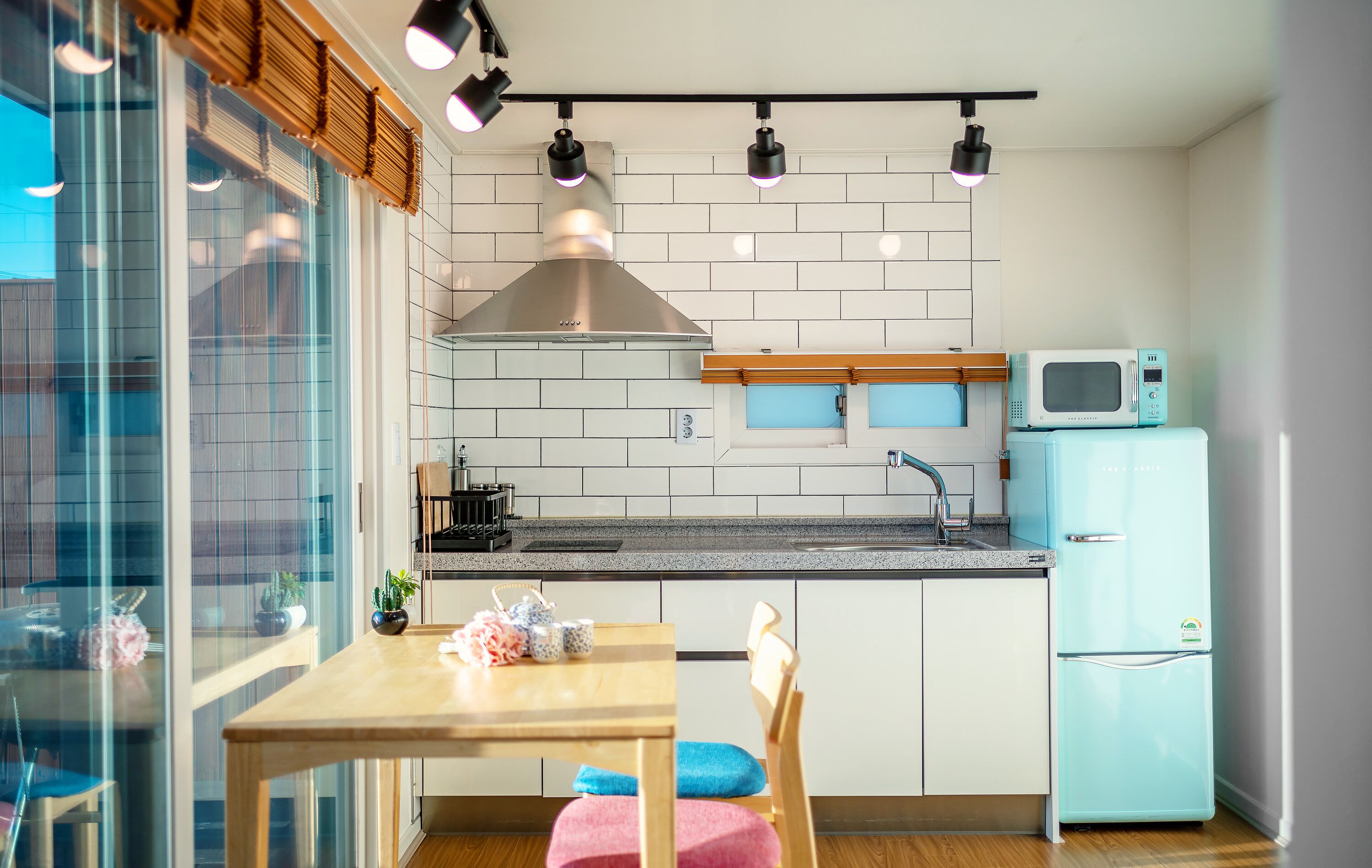 Una cocina moderna con una mesa de madera, sillas, un microondas y un refrigerador.