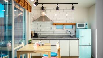 Una cocina moderna con una mesa de madera, sillas, un microondas y un refrigerador.