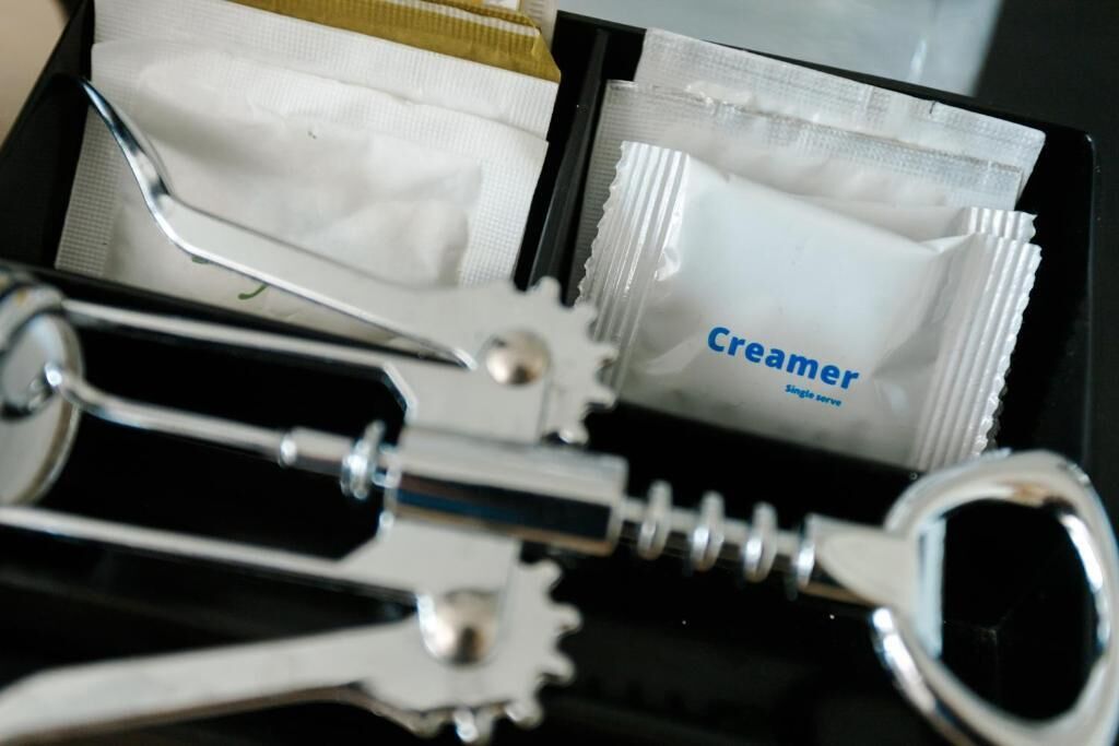 A black box containing a tube of cream and a metal tool.