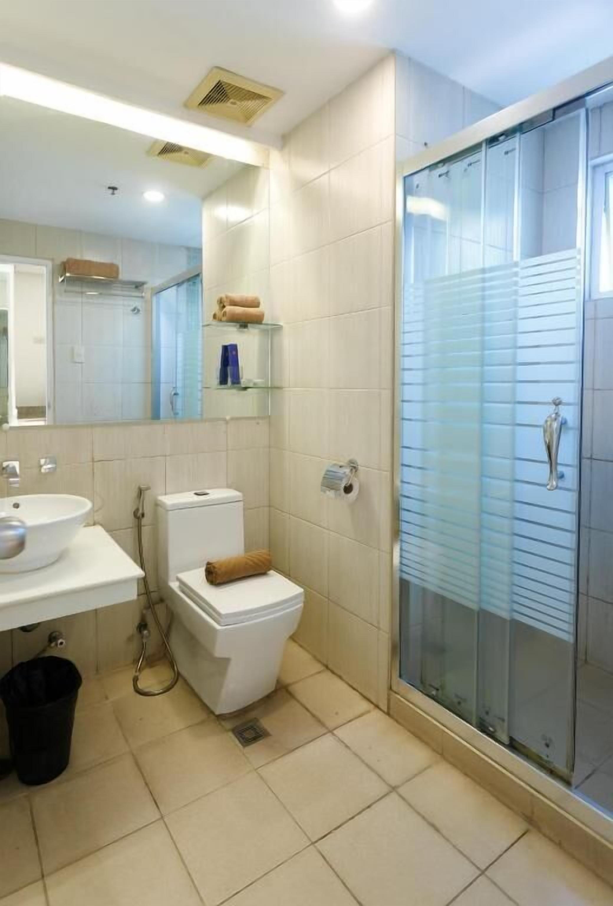 A modern bathroom with a glass shower enclosure, a white sink, and a toilet.