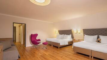 A hotel room with two beds, a sofa, a chair, and a small table.
