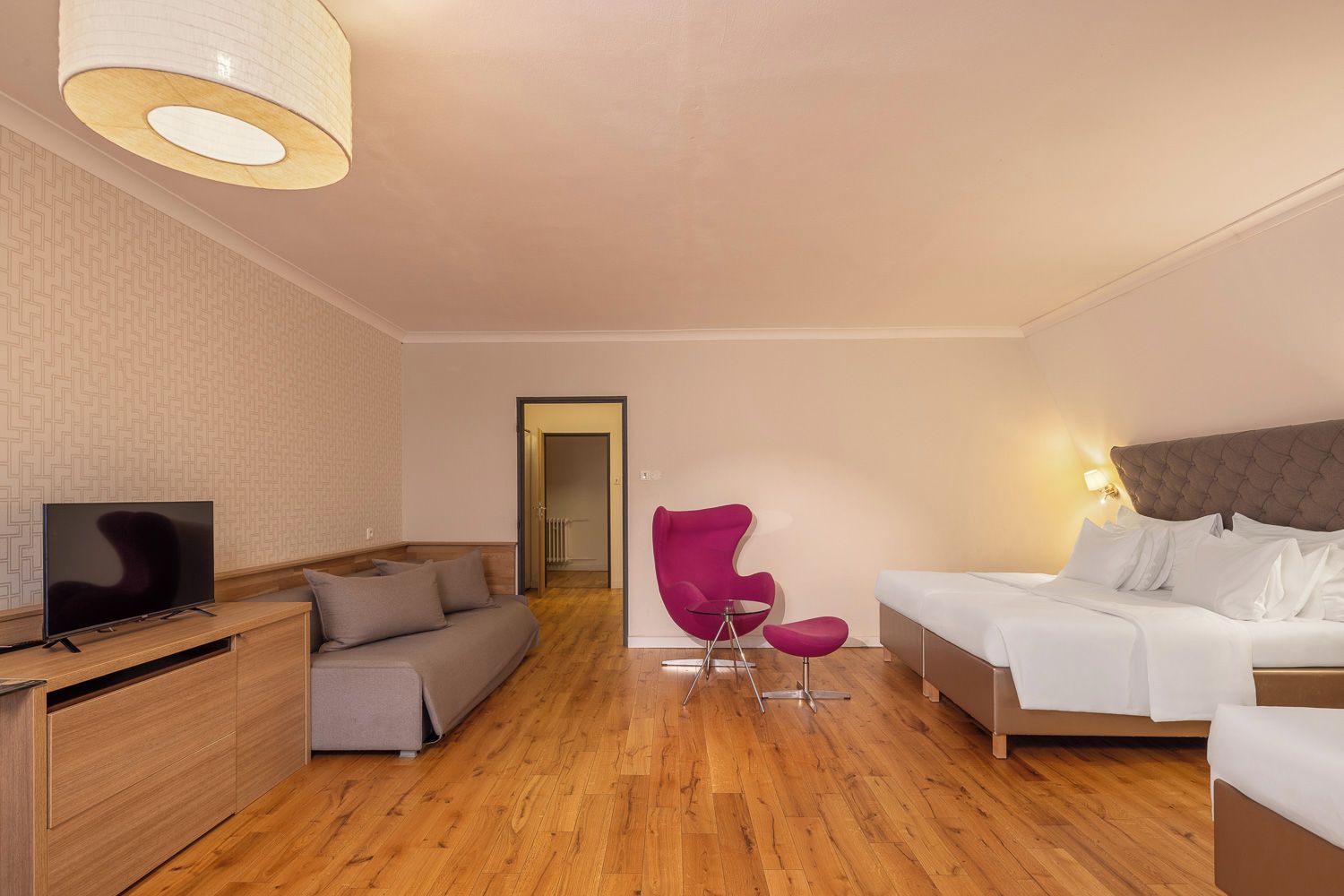 Une chambre d’hôtel avec un lit, un canapé, une télévision et un fauteuil.