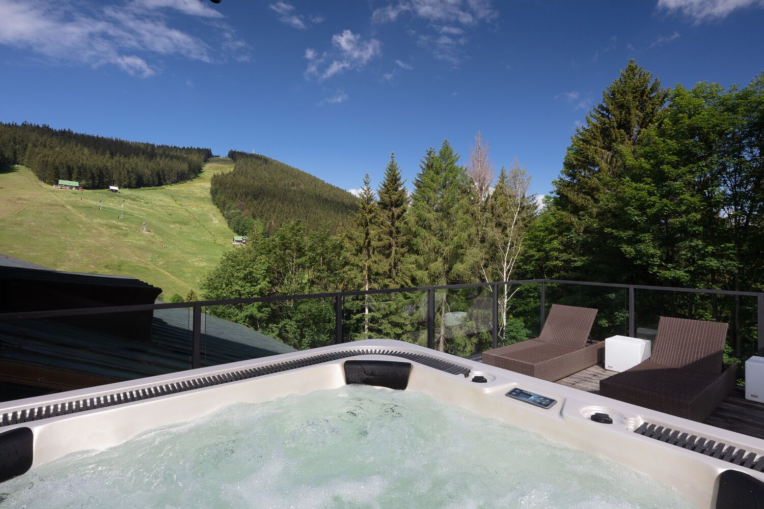 A hot tub with a view of a forested hillside.