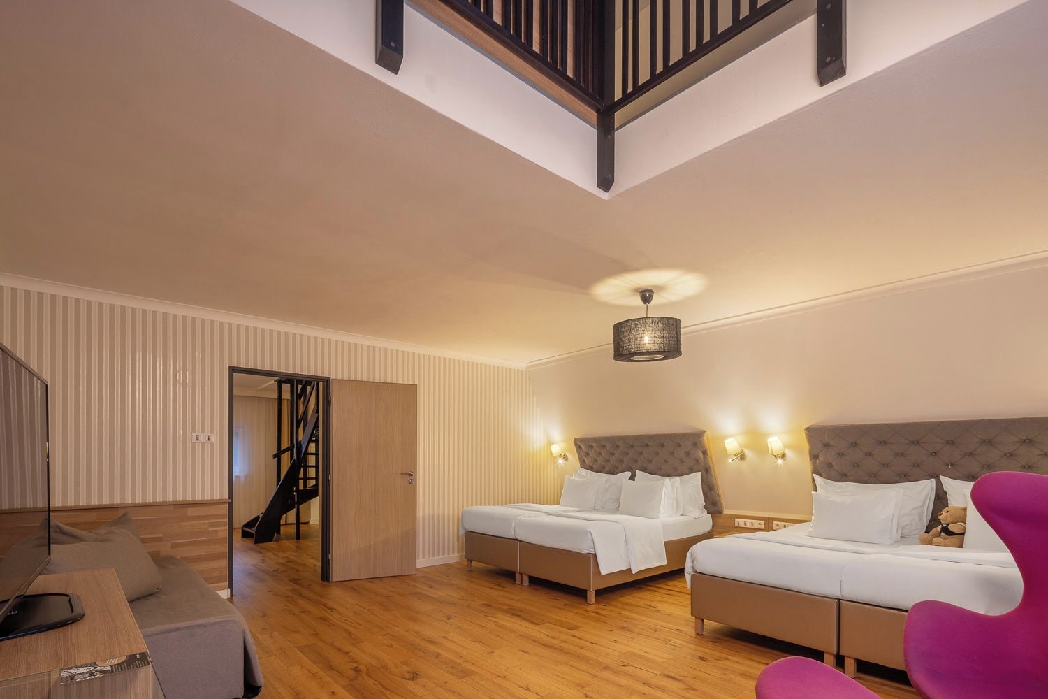 A bedroom with two beds, a staircase, and a wooden floor.