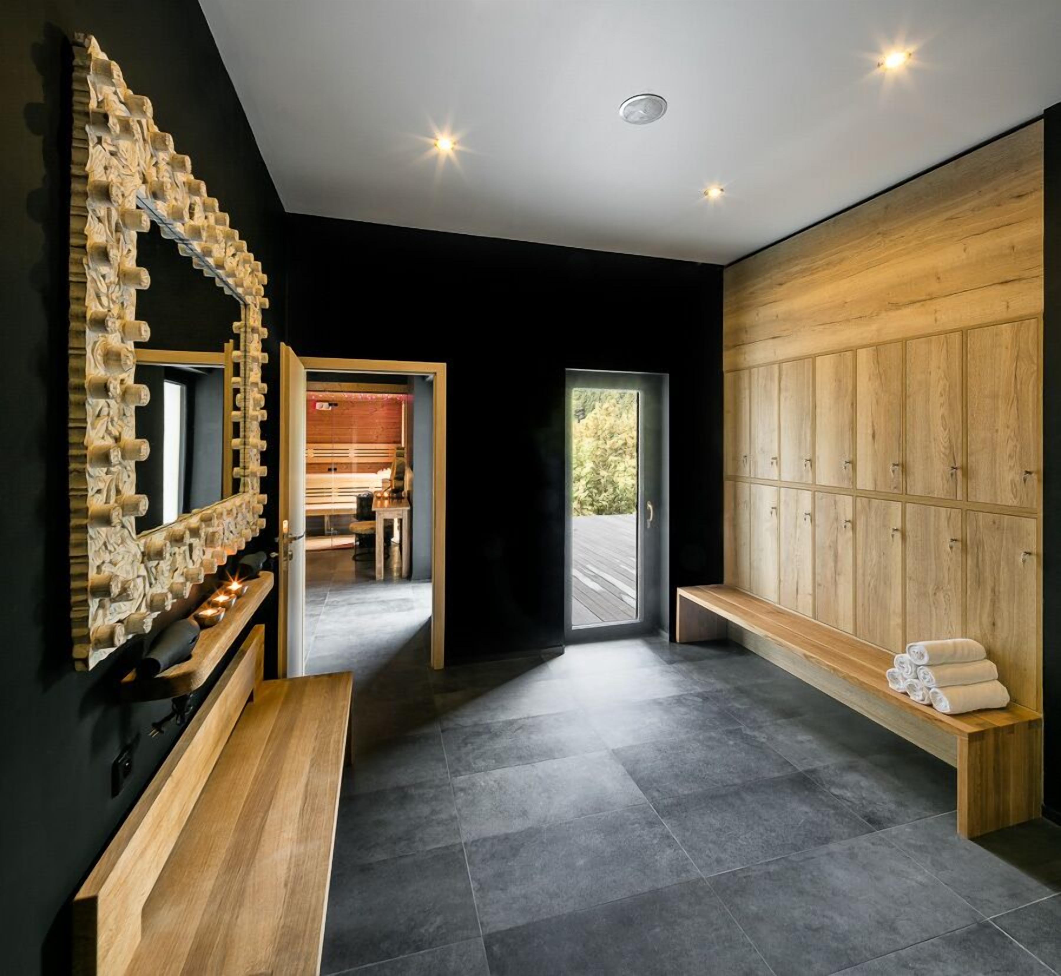 A modern bathroom with a wooden bench, a large mirror, and a sauna area.