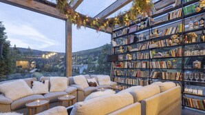 A cozy seating area with a large bookshelf filled with books and decorative items, overlooking a scenic landscape. - Pytloun Wellness Hotel Harrachov (Harrachov)