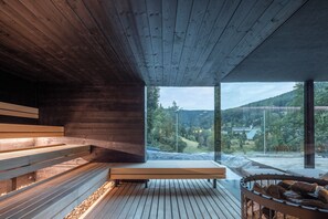 A wooden interior with benches and a view of a forested landscape.