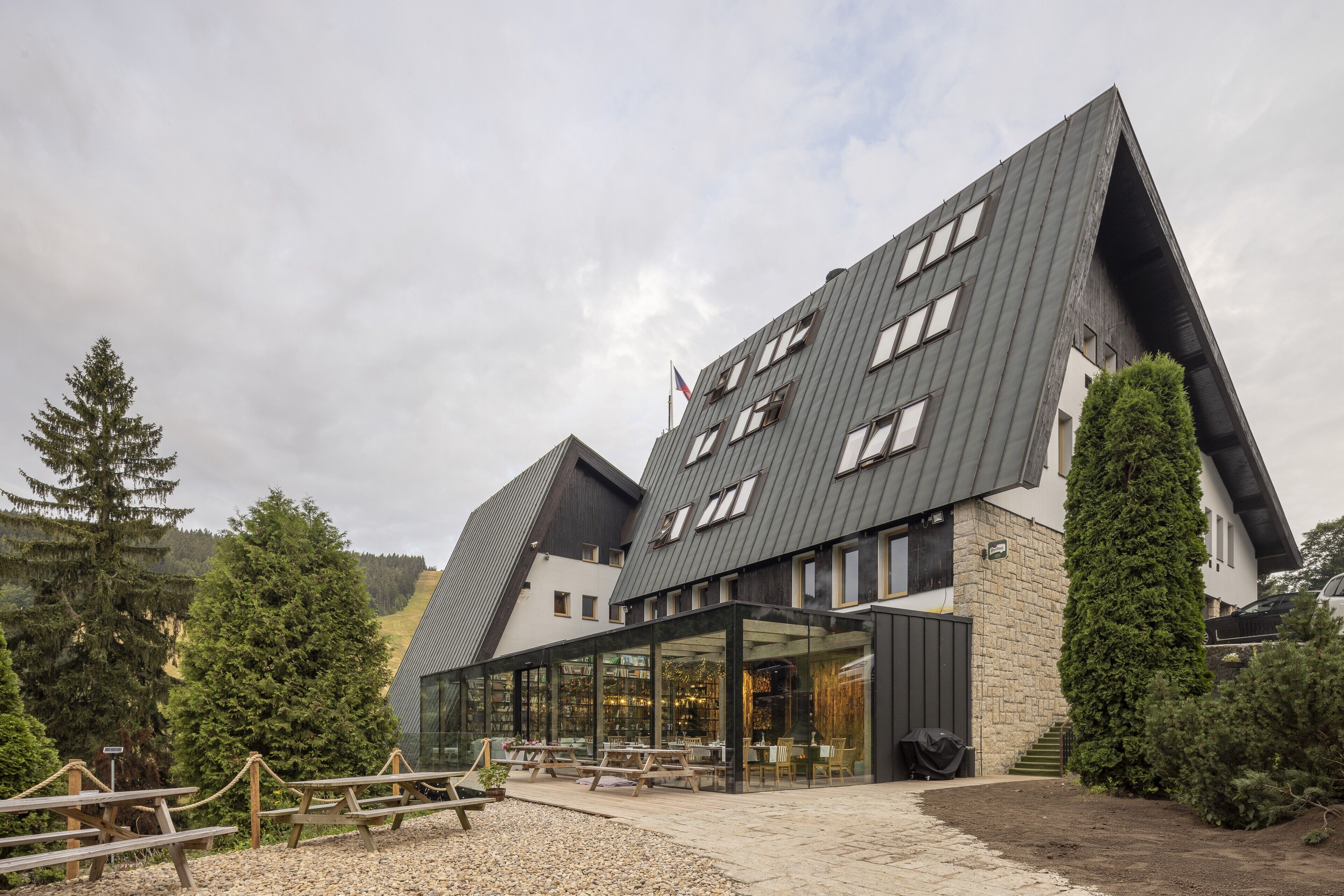 A modern building with a sloped roof, large windows, and a covered outdoor seating area.