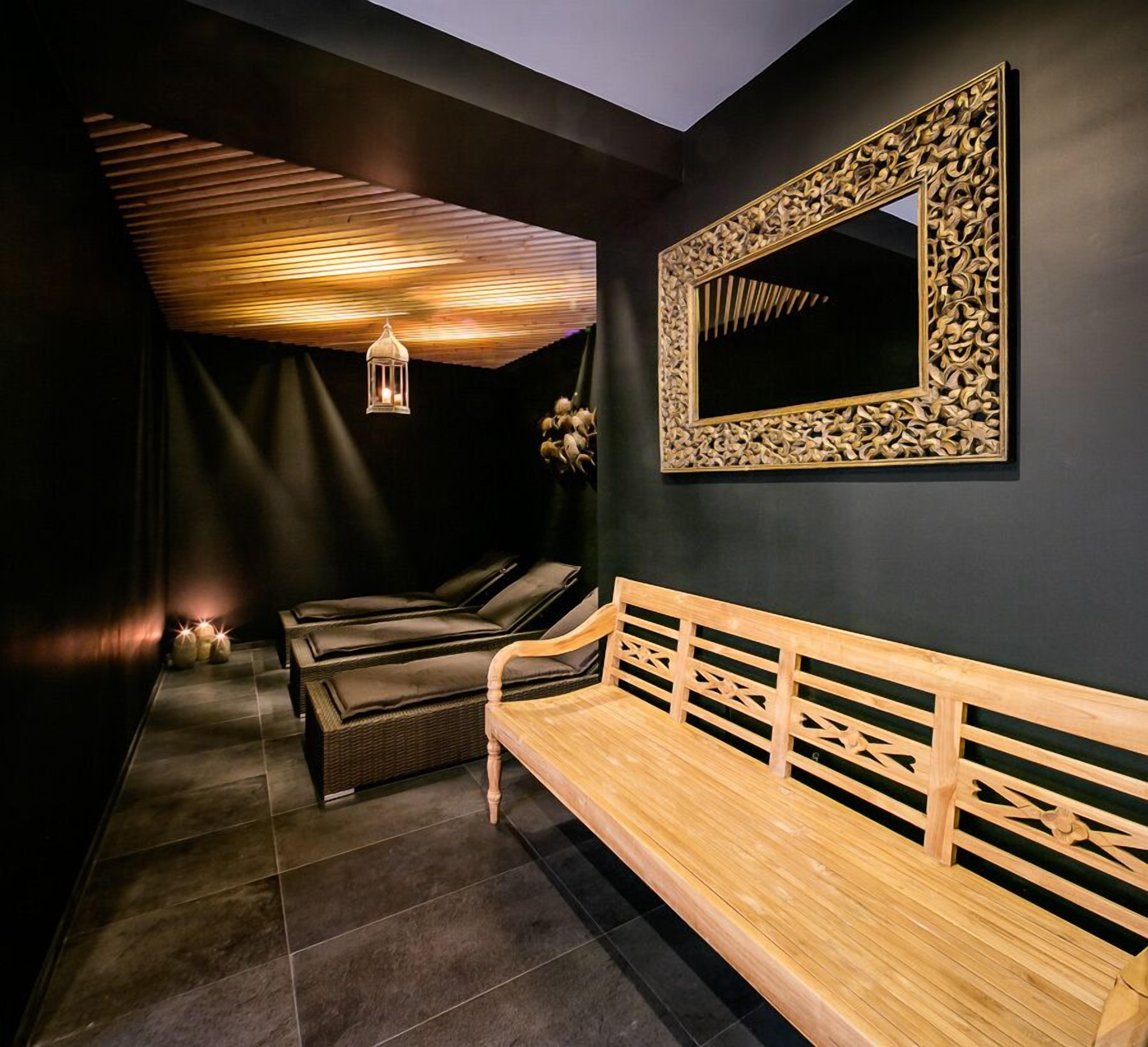 Un spa moderno con un banco de madera, un espejo fijado a la pared con intrincados grabados y un techo de listones de madera.