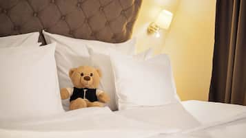 A bed with white bedding and a teddy bear in the center.