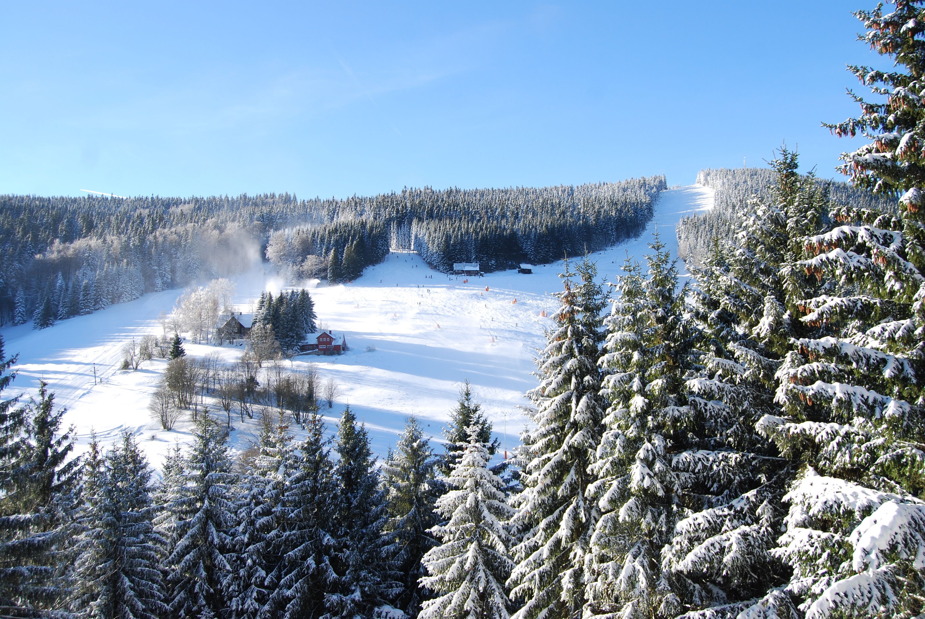 Een besneeuwd berglandschap met een skigebied, inclusief skipistes en een berghut.