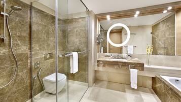 Een moderne badkamer met een douche in glazen cabine, een toilet, een wastafel met opbergruimte en een bad.