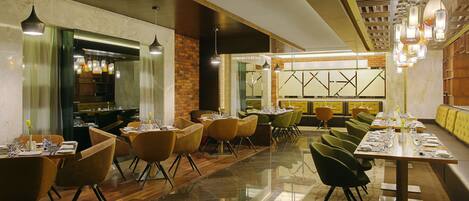 Un restaurante con una decoración moderna, que combina elementos de madera y ladrillo, un suelo de mármol pulido y diferentes opciones de asientos, incluyendo mesas y sillas.