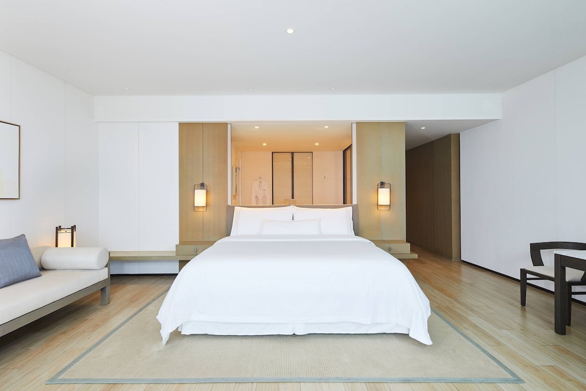 Une chambre d’hôtel moderne avec un grand lit, un canapé et un fauteuil.