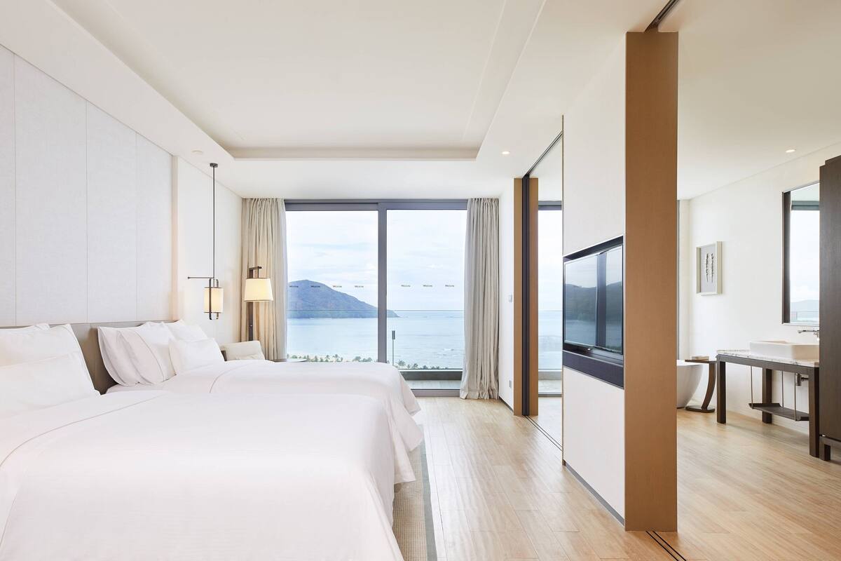 Une chambre d’hôtel avec un grand lit, un bureau et une vue sur la mer.