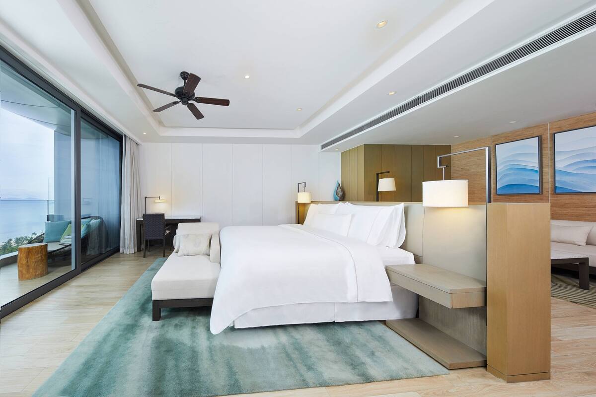 Une chambre d’hôtel moderne avec un grand lit, un bureau et une vue sur l’océan.