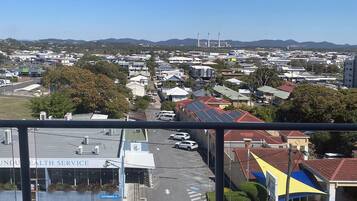 A view of a cityscape with a clear sky, a hospital building, and a road with parked cars.