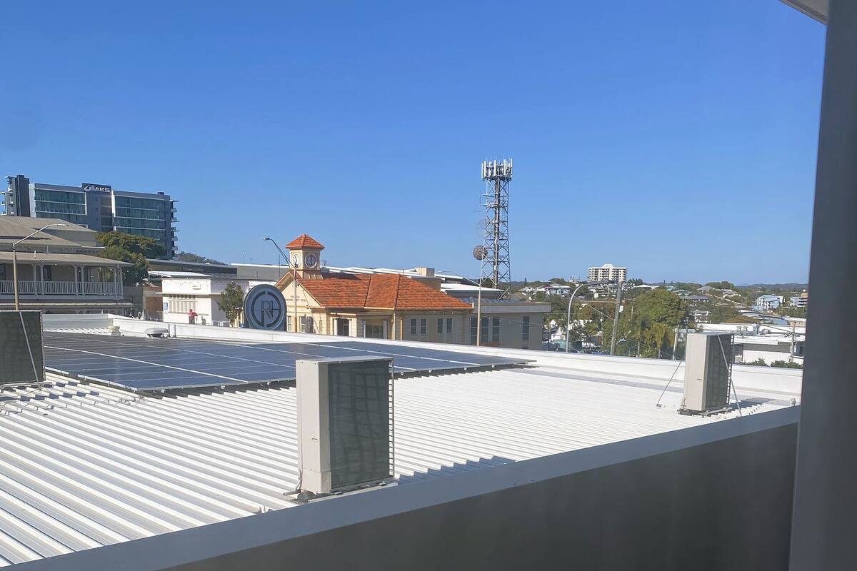 A rooftop with solar panels, a clock tower, and a communication tower.