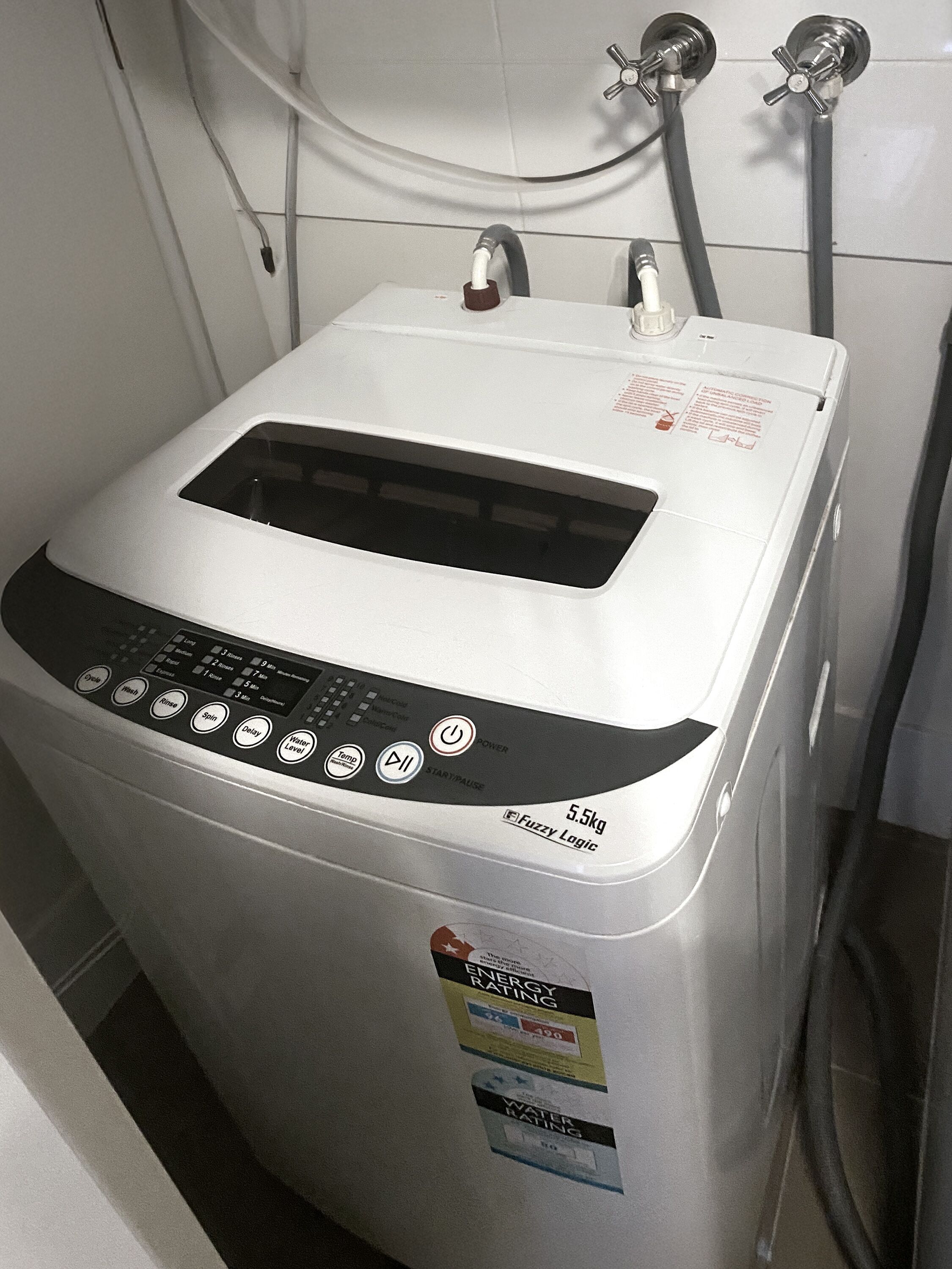 Una lavadora compacta y moderna con un panel de control que tiene varios botones para distintas funciones.