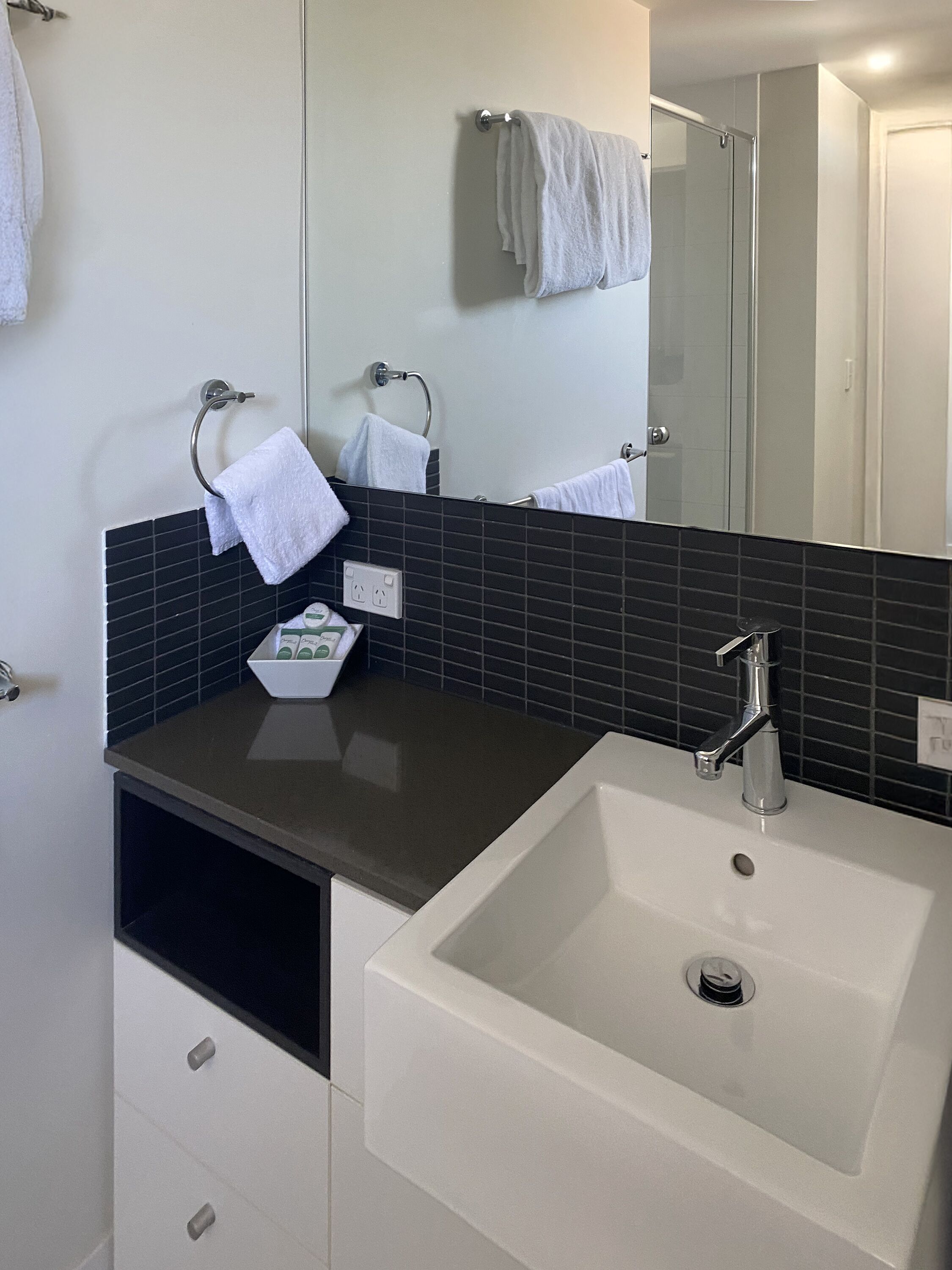 A bathroom with a white sink, a mirror, and a towel rack.