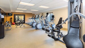 A gym with various exercise machines, a television, and a mirror. - Homewood Suites By Hilton San Bernardino (San Bernardino)