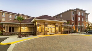 A hotel entrance with a stone facade, a palm tree, and a clear sky. - Homewood Suites By Hilton San Bernardino (San Bernardino)