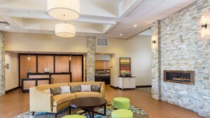 A lobby with a sofa, ottomans, a fireplace, and a reception desk. - Homewood Suites By Hilton San Bernardino (San Bernardino)