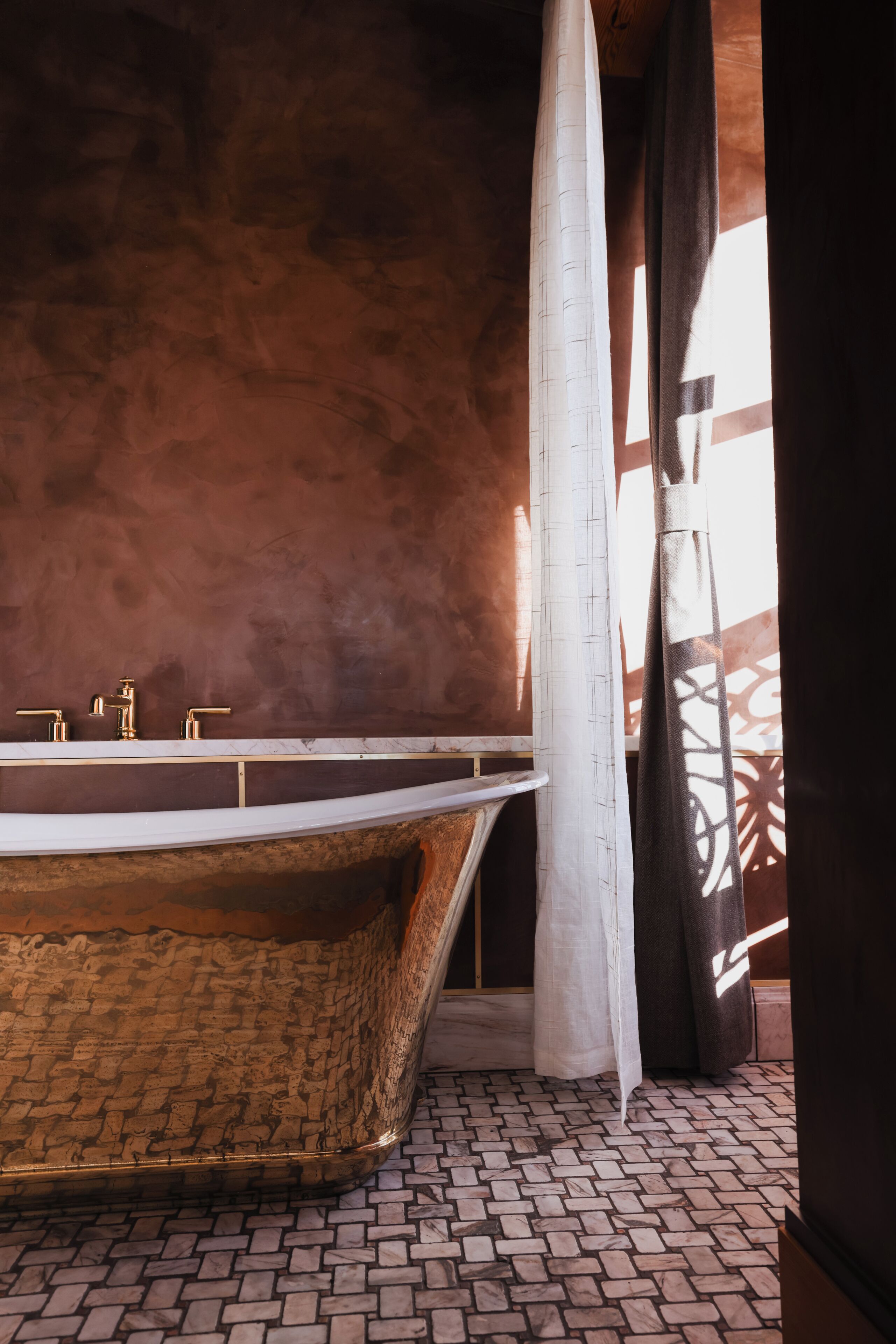 Une salle de bain avec une baignoire, un lavabo fixé au mur et un carrelage décoratif.