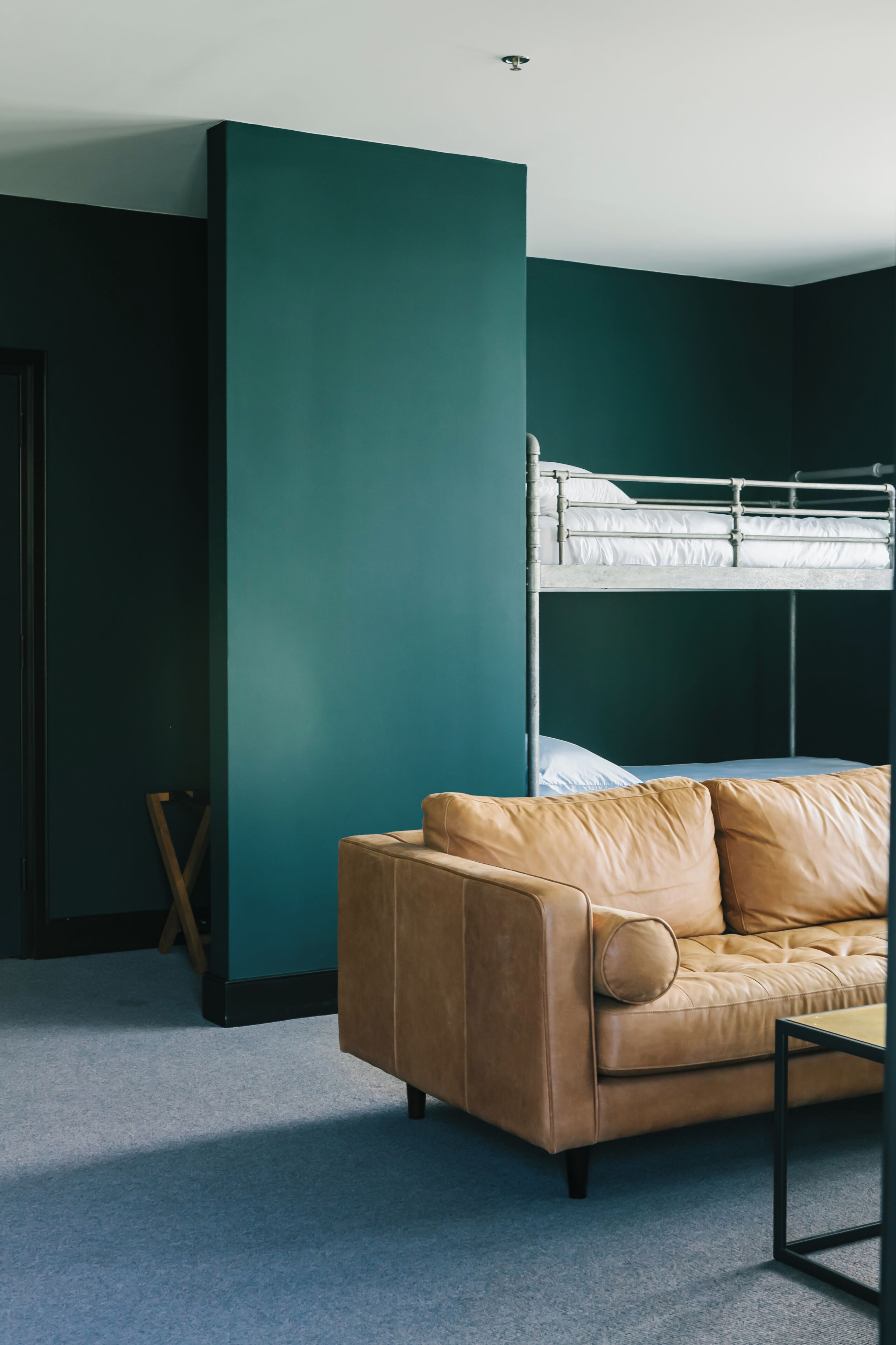 A room with a bunk bed, a leather sofa, and a small table.