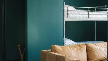 Una habitación con una cama litera, un sofá de cuero y una mesita.