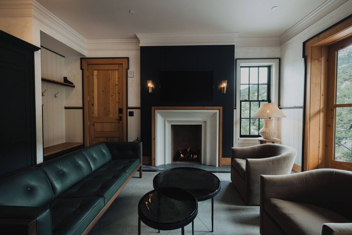 Een woonkamer met een open haard, een bank, twee fauteuils en een salontafel.