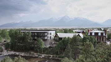 A modern building with a stone facade, surrounded by lush greenery and a river.