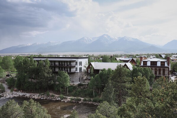 A modern building with a stone facade, surrounded by lush greenery and a river. - Surf Hotel & Chateau (Buena Vista)