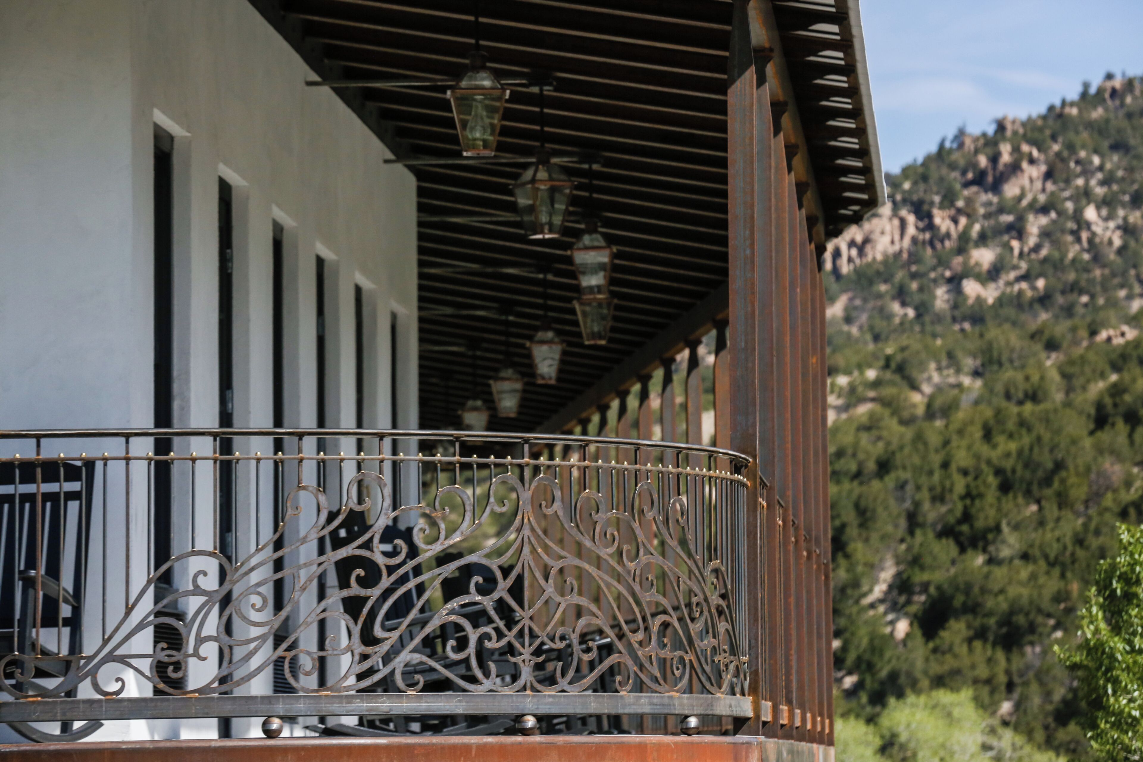 A balcony with ornate metal railings, a wooden ceiling, and hanging lanterns.