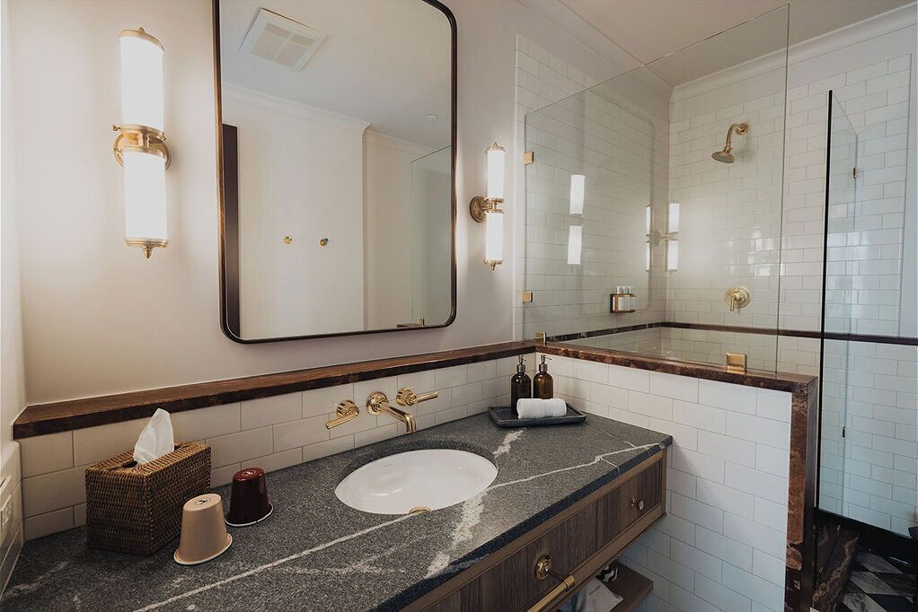 A bathroom with a large mirror, a sink, a shower, and a towel rack.