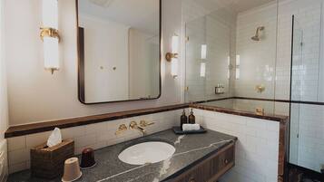 Un baño con un espejo grande, un lavabo, una ducha y un perchero para toallas.