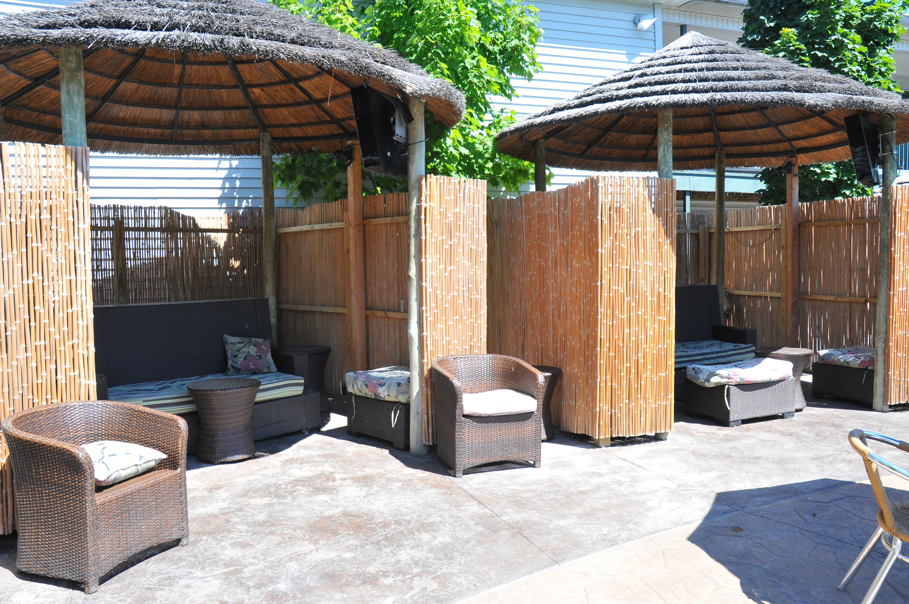 A covered outdoor seating area with wicker furniture and thatched umbrellas.