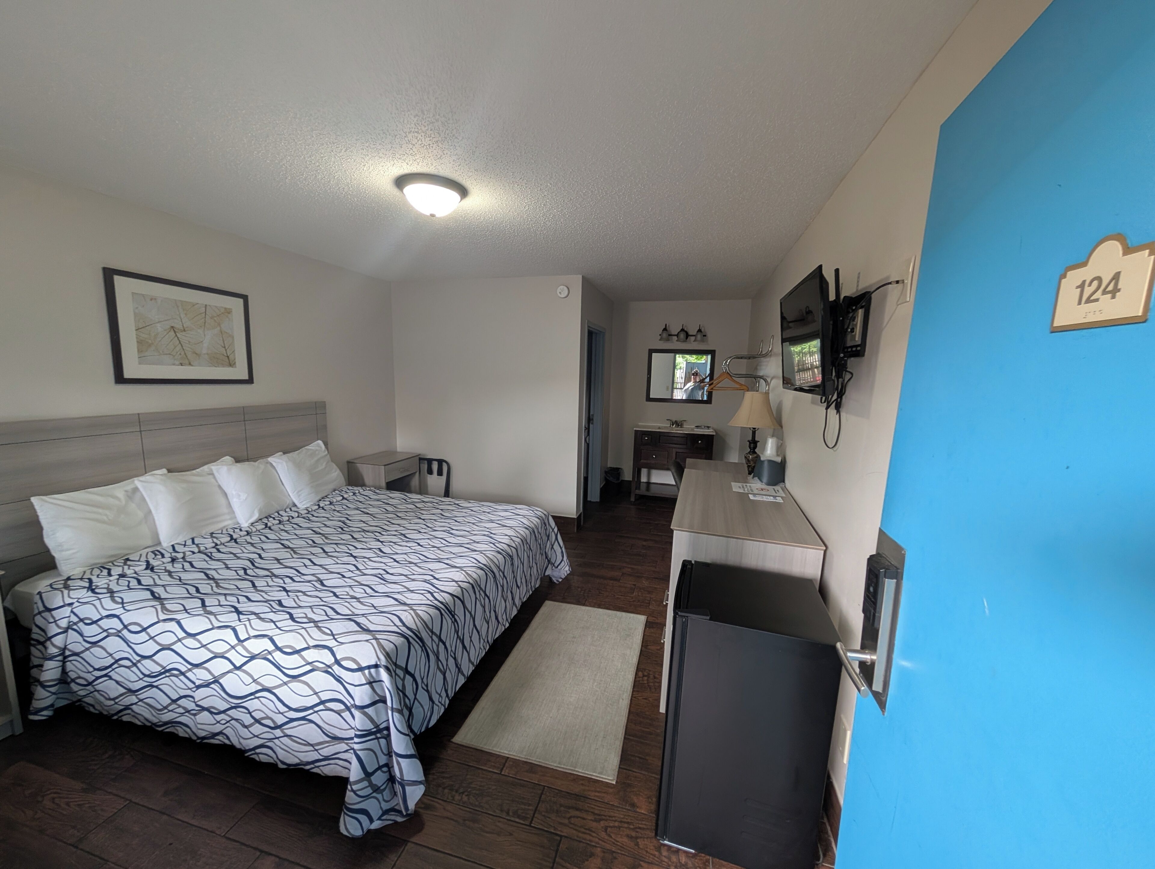 Een hotelkamer met een bed, bureau, spiegel en televisie.