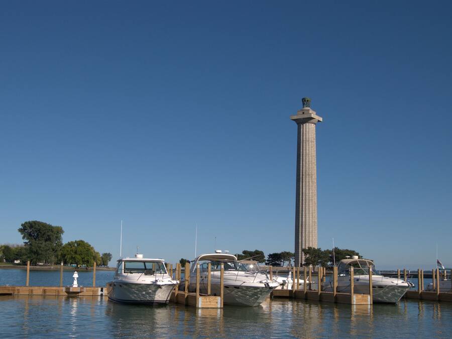 A marina with several boats docked, a tall tower structure, and a clear blue sky.
