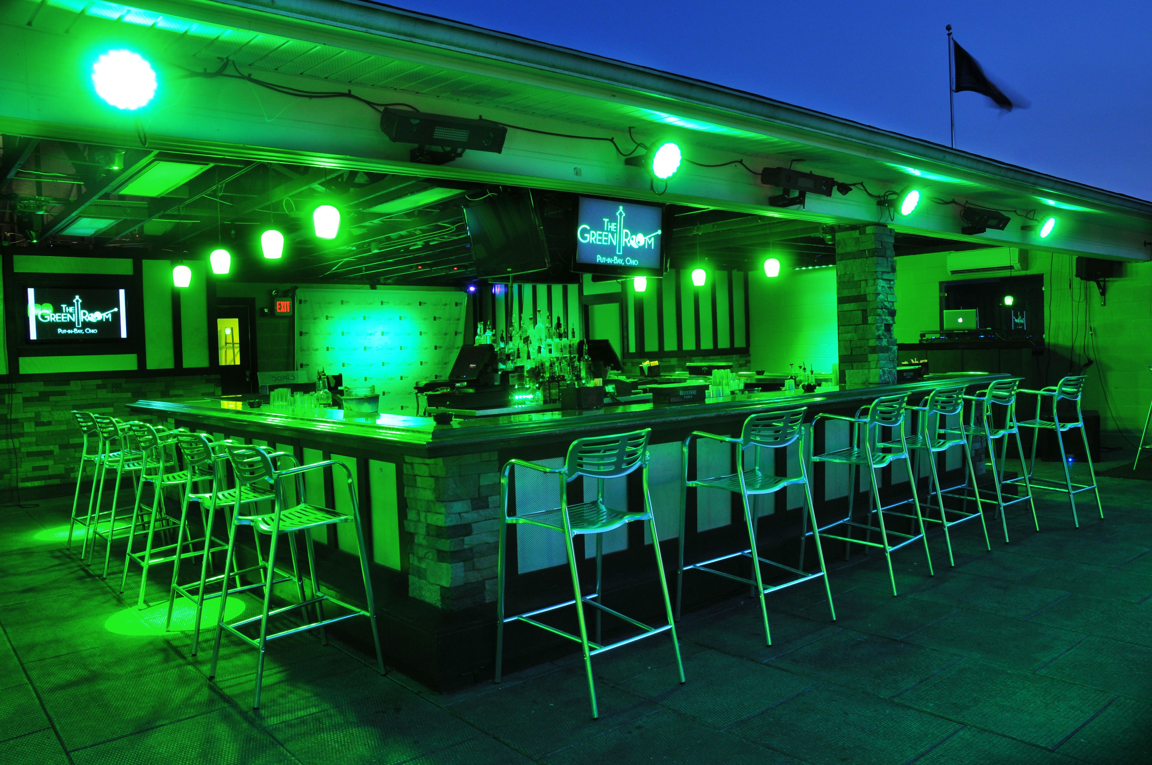A bar with a neon sign, bar stools, and a stone counter.