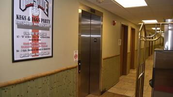 A hallway with a sign for Ohio State's Kegs & Eggs Party, an elevator, and a trash can.