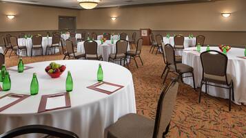 A conference room with multiple tables, chairs, and green bottles.