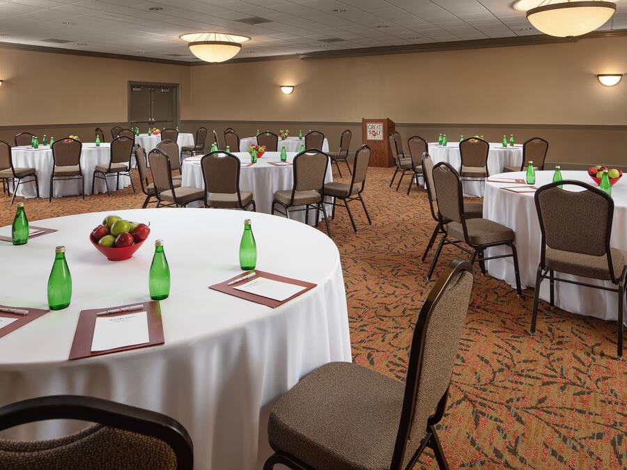 A conference room with multiple tables, chairs, and green bottles.